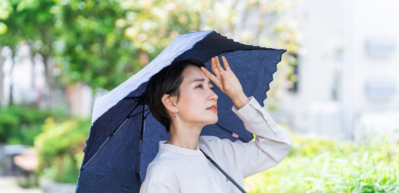 日傘をさして汗をかいている女性