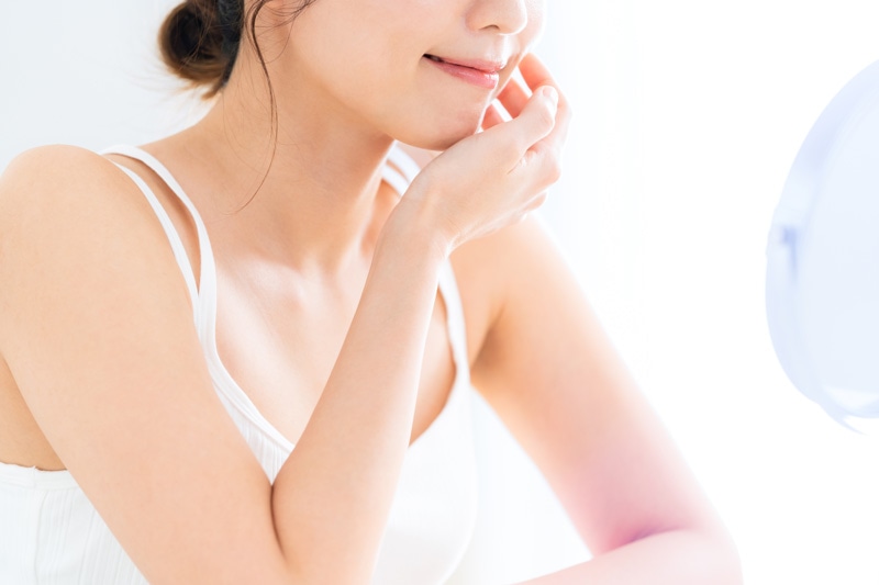 鏡を見て肌を触る女性