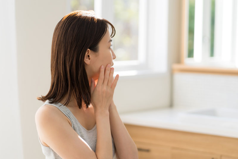 鏡を見て肌を触る女性